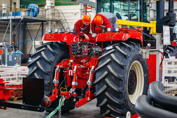 Industrial workers assembles agricultural tractor in workshop