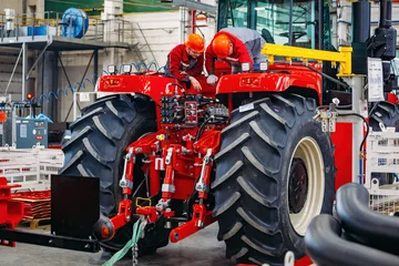 Crédence de cuisine en verre imprimé Tracteur Industrial workers assembles agricultural tractor in workshop