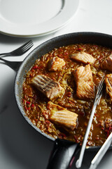 Frying pan with Indian salmon curry dish. Fried salmon fillets, stewed in curry sauce based on red tomatoes and other vegetables.