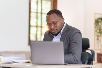 Fototapeta na wymiar Tired American African business man in stress works with many paperwork document. migraine attack. Freelance, work from home