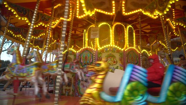 The camera zooms in on a bright carousel at an amusement park