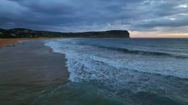 Aerial sunrise with cloud filled sky and waves at  Macmasters Beach on the Central Coast, NSW, Australia.