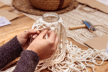 White macrame. Young girl fixes the macrame knots so that they do not unravel.