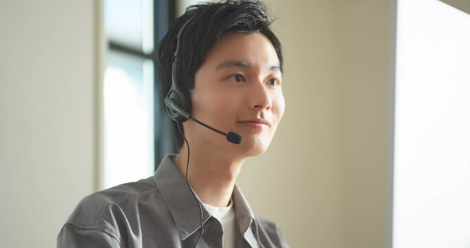 ヘッドセットをつけてオンライン会議をする若いビジネスマンの男性