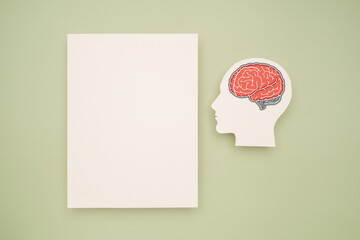 A blank white paper and a red brain shape symbol on a green background
