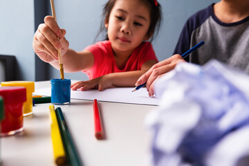 Asian kid learning with drawing on empty sheet of white paper