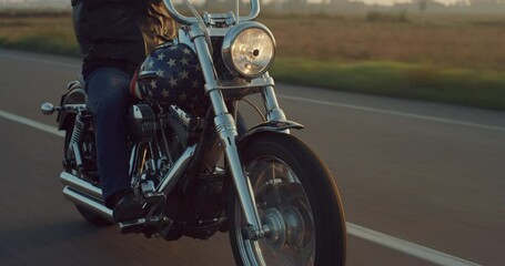 Close Up on a Vintage Custom Motorbike with American Flag Paint Driving on a Countryside Highway. Motorcyclist with Leather Jacket Riding his Motorcycle, Enjoying his Freedom, Doing a Road Trip