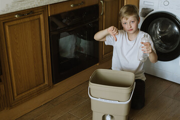 Negative emotion. Boy show don't put plastic bottle into bucket compost. Zero waste concept. Processing and recycling organic.