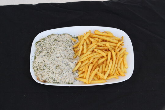 Culinary Delight: Chicken in Savory Sauce and Golden Fries on Dark Background