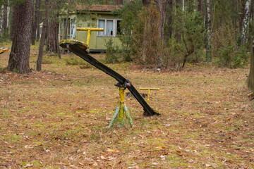 An old, dilapidated children's swing in an abandoned and forgotten holiday resort in the forest. Urbex.