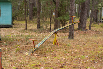 An old, dilapidated children's swing in an abandoned and forgotten holiday resort in the forest. Urbex. - 583466310