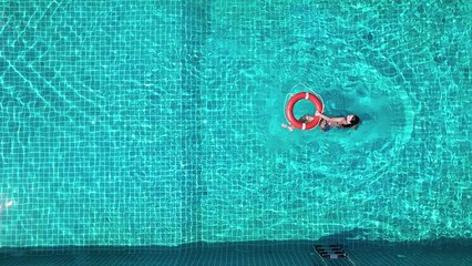 A view of a lifeguard girl training with a life preserver swimming in the pool.