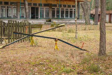 An old, dilapidated children's swing in an abandoned and forgotten holiday resort in the forest. Urbex.