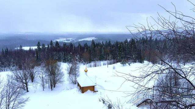 View of the chapel near the Belogorsky St. Nicholas Orthodox Missionary Monastery. Winter forest. The temple on the hill in winter. Russia, Perm Krai, Belaya Gora. 4K