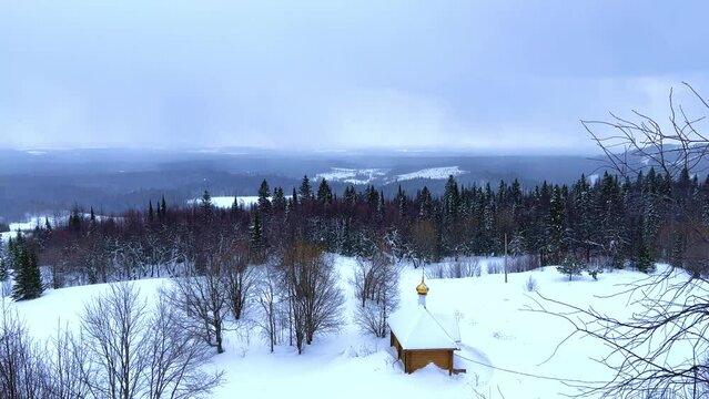 View of the chapel near the Belogorsky St. Nicholas Orthodox Missionary Monastery. Winter forest. The temple on the hill in winter. Russia, Perm Krai, Belaya Gora. 4K