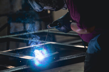 Industry worker welding iron pieces at work