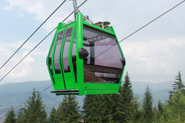 A view of a cabins of the Sarajevo ropeway over the forest in a background of Trebevic mountain