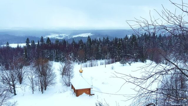 View of the chapel near the Belogorsky St. Nicholas Orthodox Missionary Monastery. Winter forest. The temple on the hill in winter. Russia, Perm Krai, Belaya Gora. 4K