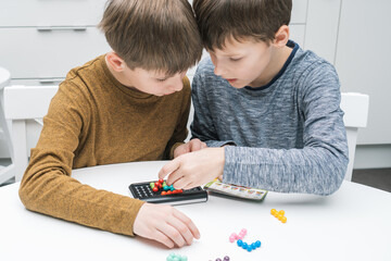Two pensive and enthusiastic boys playing educational, strategy board game with black field and...