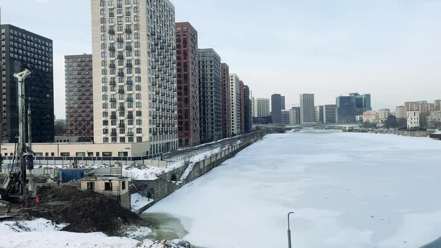 View From Window Of Train Or Commuter On Moscow River In Winter In Ice, High Rise Buildings And Construction Site. Train Slowly Moving Along Rails Gaining Speed, View From Inside. No People.