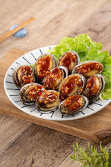 Delicious steamed abalone with Taiwanese five flavor sauce on wooden table background.