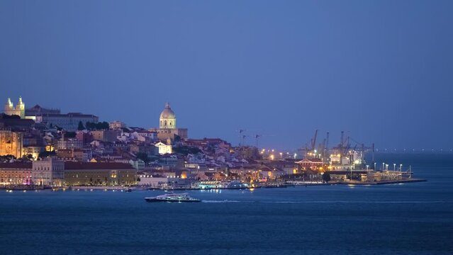 View of Lisbon over Tagus river with passing ferry boat from Almada with ferry in evening twilight. Lisbon, Portugal