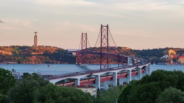Time-lapse of Lisbon view from Miradouro do Bairro do Alvito tourist viewpoint with Tagus river, traffic on 25th of April Bridge and Christ the King statue on sunset. Lisbon, Portugal. Zoom in effect