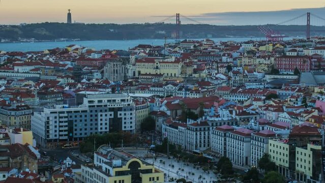 Day to night time-lapse of Lisbon famous view from Miradouro da Senhora do Monte tourist viewpoint over Alfama old city district, 25th of April Bridge. Lisbon, Portugal. Camera pan effect