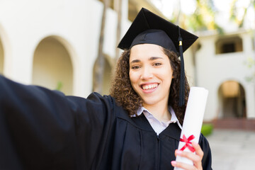 Attractive young woman taking a selfie graduating university
