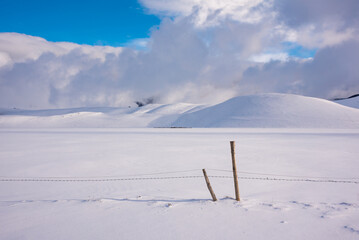 Winter landscape, wooden fence in snow valley on bright sunny day