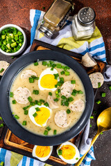 White Eastern European borscht. Traditional Polish white soup Zurek, with sausages, egg, herbs and green onions