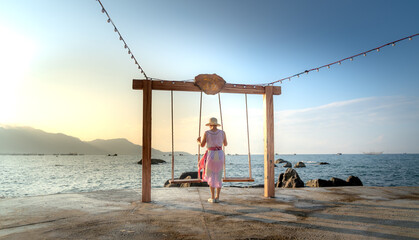 A female tourist relaxes on a swing at a tropical beach at 4-star Hon Co Resort, Ca Na in Ninh province. Thuan, Vietnam. She feels comfortable and happy with the scenery here