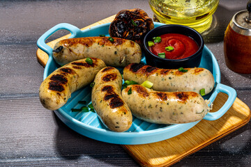 Grilled white chicken, pork meat sausages, ready bbq Munich, Greisinger or Wurst sausages with tomato sauce. Summer barbeque party background, top view copy space
