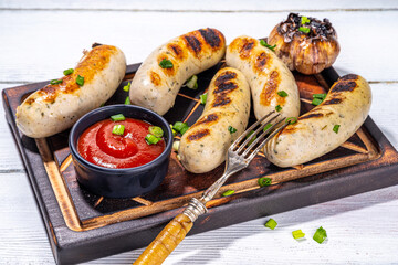 Grilled white chicken, pork meat sausages, ready bbq Munich, Greisinger or Wurst sausages with tomato sauce. Summer barbeque party background, top view copy space