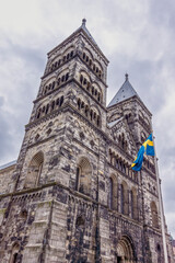 Fototapeta na wymiar The towers of Lund cathedral and a Swedish flag against the sky