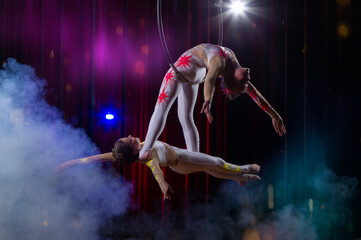 Circus acrobats gymnasts perform on a stage dark background.
