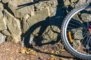 Fototapeta na wymiar Bicycle wheel and stone wall. Active recreation by bike.