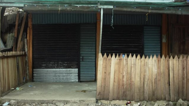 Hand held shot of a closed wooden storefront of a fisherman's shop in a rustic street market, in Buenaventura