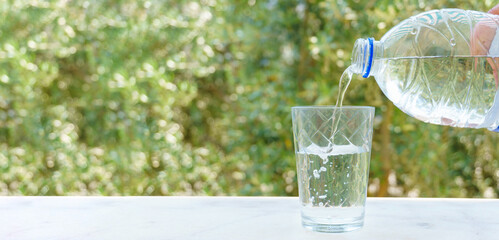 Pouring water into the glass on nature background. Beautiful large and high resolution photo for displays, prints.