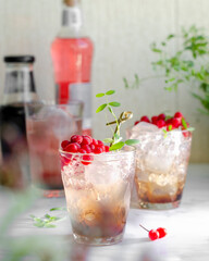 lingonberry cocktail with ice and chocolate in beautiful glasses, branch in blur