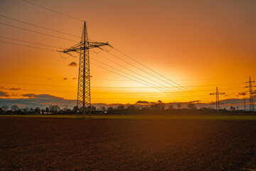 Strommast bei Sonnenuntergang mit Feld