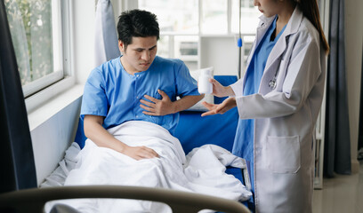 Obraz premium Doctor and young male patient who lie on the bed while checking pulse, consult and explain with nurse taking note in hospital