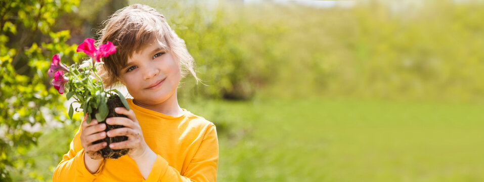 Spring awakening. Enjoying the little things. Dreaming of spring. child with flowers in the garden. Child girl plant flowers in the garden near the home on spring day. banner. copy space