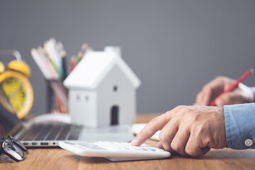 House purchase and cost idea, Home interest calculate concept. Man using calculator on office desk to plan and find the number of money for house financial. Residence buying planning.