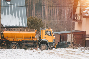 Gritter working on the suburban street after heavy snowfall. Snow clearing on the roads. Salt...