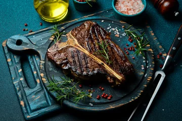 Foto op Canvas Grilled T-bone steak. Beef steak on a wooden black plate. Meat. © Yaruniv-Studio