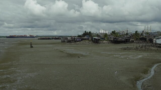 Wide angle of a container ship  in the distance passing by a poor neighborhood in Buenaventura, Colombia.