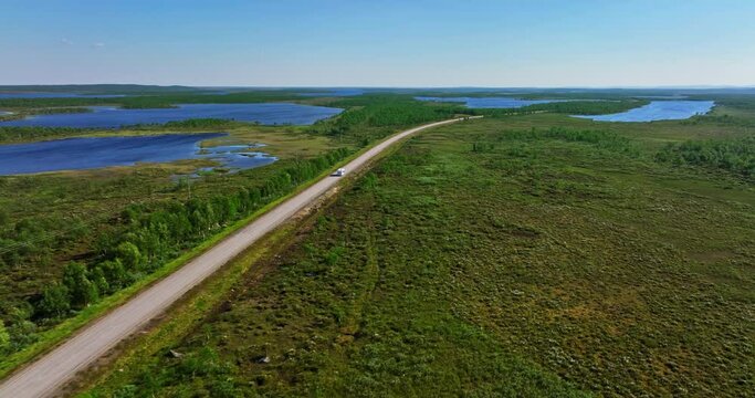 Aerial view tracking a campervan driving in boreal nature of North Scandinavia