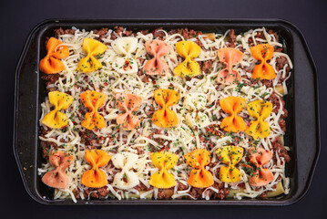 pasta with meat and cheese in a baking dish on a dark background