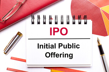 On the desktop is a white notebook with the text IPO Initial Public Offering